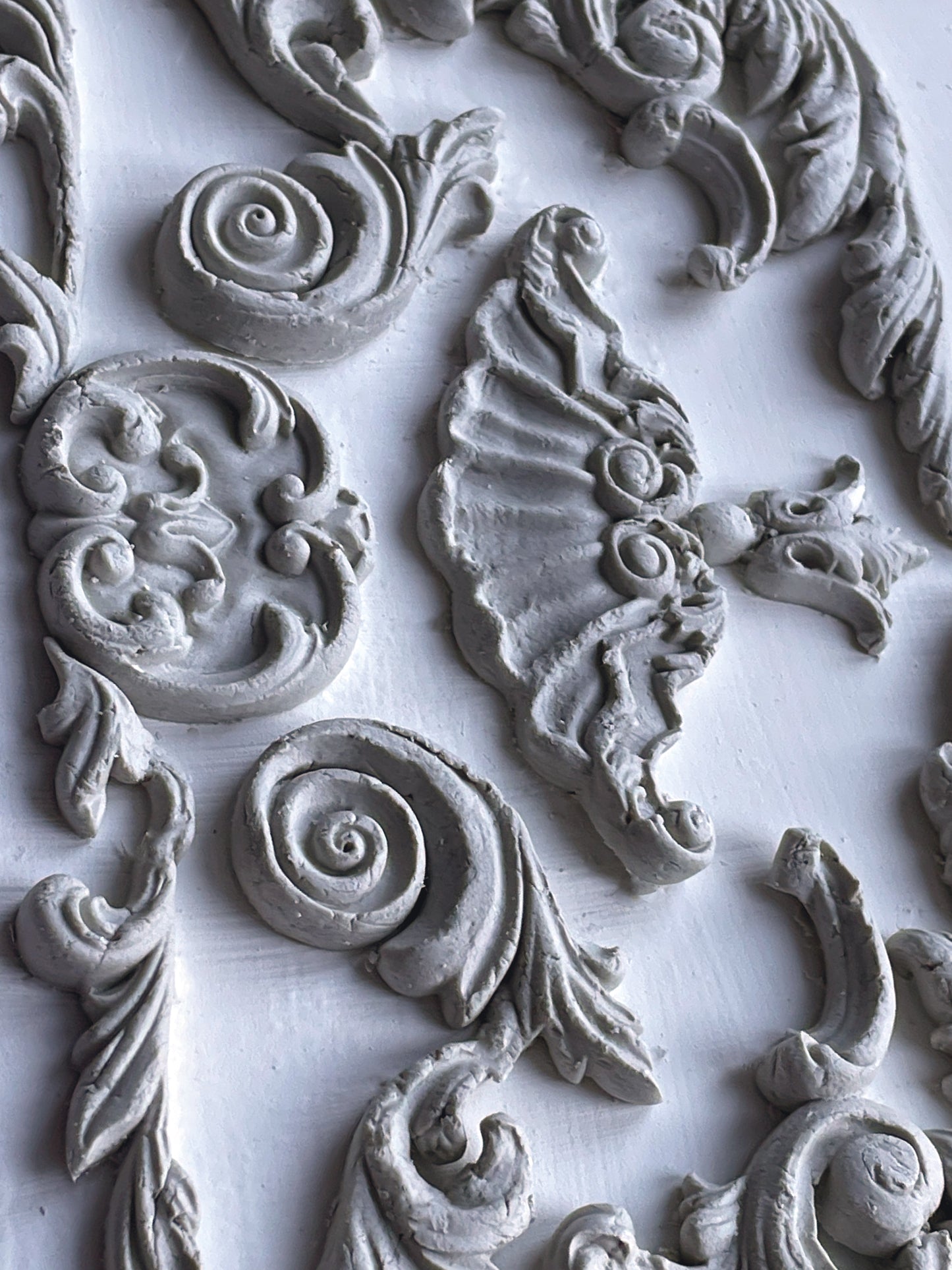 Finished castings from IOD Dainty Flourishes Mould — baroque scrolls, acanthus leaves, shell and spiral motifs in grey clay